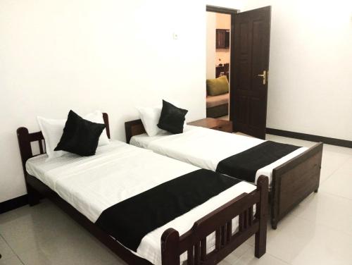two beds with black and white sheets in a room at Ceylander Suites in Kandy