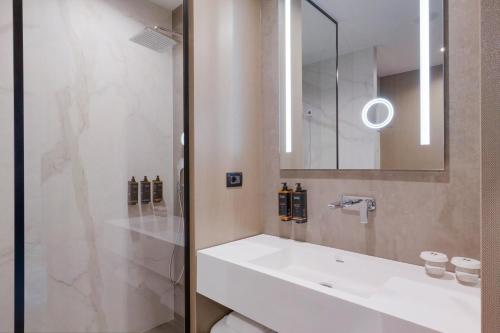 a bathroom with a white sink and a mirror at Mercure Oradea in Oradea