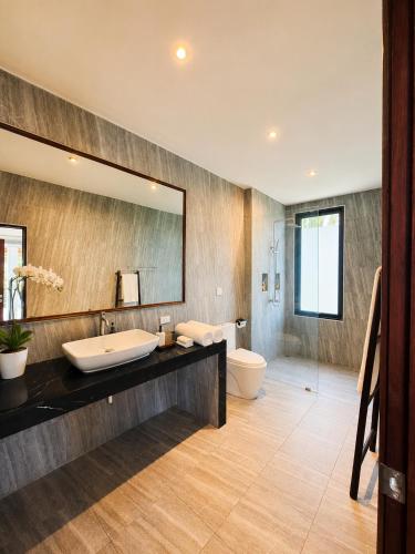 a bathroom with a sink and a toilet and a mirror at Mirari Villa in Wok Tum