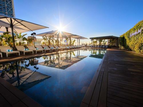 a swimming pool with chairs and umbrellas in a resort at Sofitel Barcelona Skipper in Barcelona