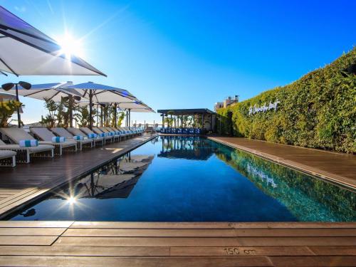 a pool with chairs and umbrellas at a resort at Sofitel Barcelona Skipper in Barcelona