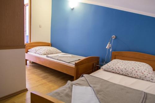 two beds in a room with a blue wall at Marea in Veli Lošinj
