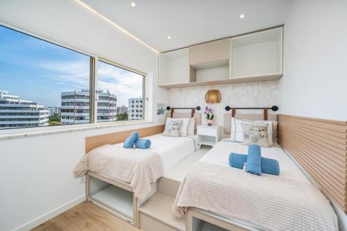two beds in a room with a large window at Mar & Sol Penthouse in Portimão