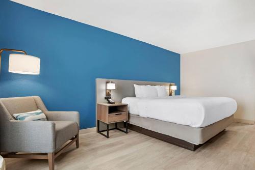 a bedroom with a blue wall and a bed and a chair at Comfort Inn & Suites Dothan Northside Plaza in Dothan