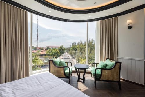 a bedroom with a bed and chairs and a large window at Can Gio Park Hotel in Cần Giờ