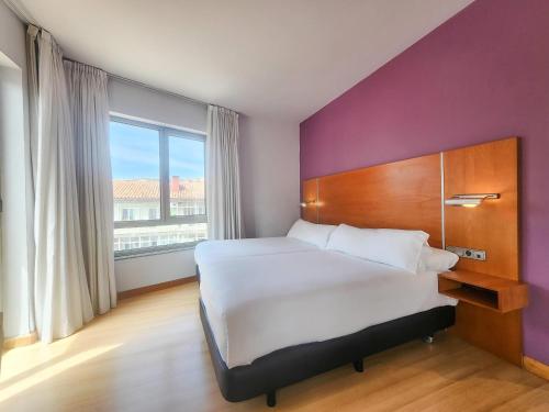 a bedroom with a large bed and a purple wall at Hotel Faranda Marsol Candas, Ascend Hotel Collection in Candás