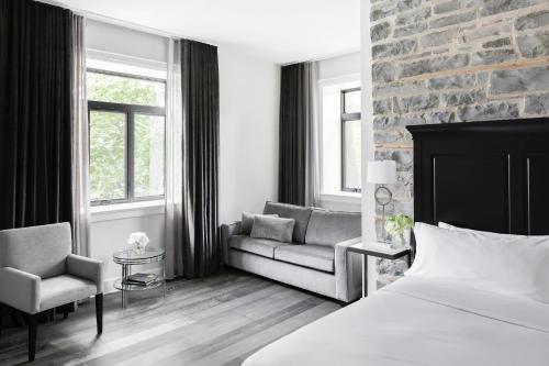 a bedroom with a bed and a couch and a chair at Frontenac Club, an Ascend Collection Hotel in Kingston