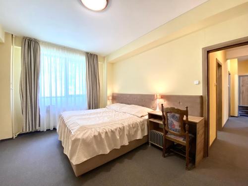 a bedroom with a bed and a desk and a window at Vila Predeal Holidays in Predeal