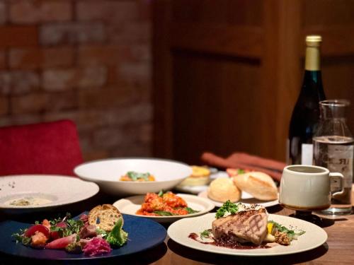 a table with plates of food and a bottle of wine at UNWIND HOTEL & BAR Okunikko in Nikko