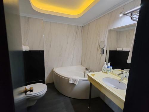 a bathroom with a tub and a sink and a toilet at Deny Inn Harmony in Zărneşti