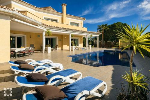 a group of lounge chairs next to a swimming pool at Villa Esplendida by Abahana Villas in Ifach
