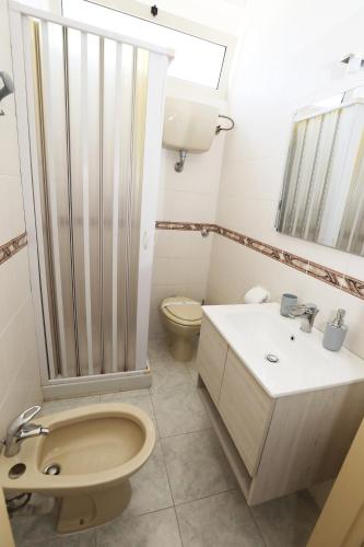 a white bathroom with a toilet and a sink at Helios Rooms in Quartu SantʼElena
