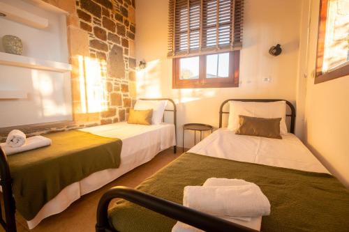 a small room with two beds and a window at Helios stone house in Aegina