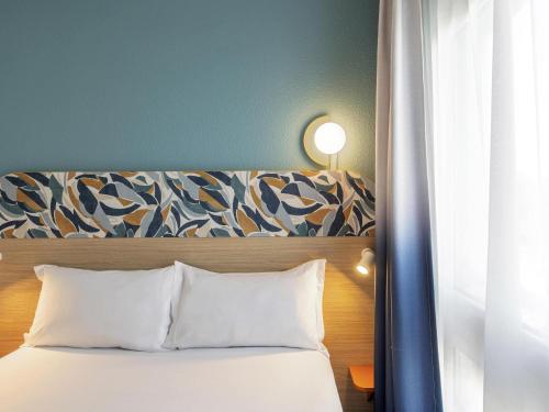 a bed with white pillows and a blue wall at Aparthotel Adagio Access Paris La Villette in Paris