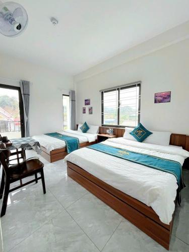 a bedroom with two beds and a chair at Lộc phát hotel mộc châu in Làng Môn