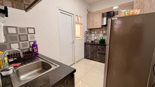 a kitchen with a sink and a stainless steel refrigerator at Krishna Cottage 3BR Apt By Amoret Homes in Chicalim