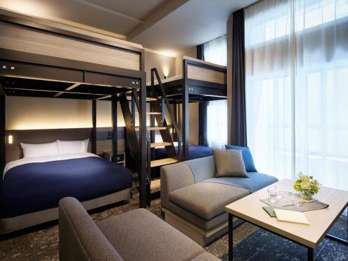 a bedroom with a bunk bed and a couch and a table at Minn Sapporo Odori W14 in Sapporo