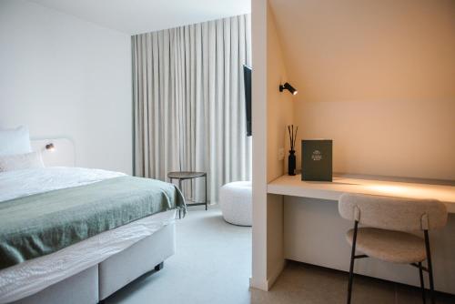 ein Schlafzimmer mit einem Bett und einem Schreibtisch mit Fernseher in der Unterkunft Between Flanders Walls in Ypern