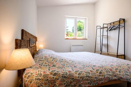 a bedroom with a bed with a lamp and a window at Flora Gîte in Kaysersberg