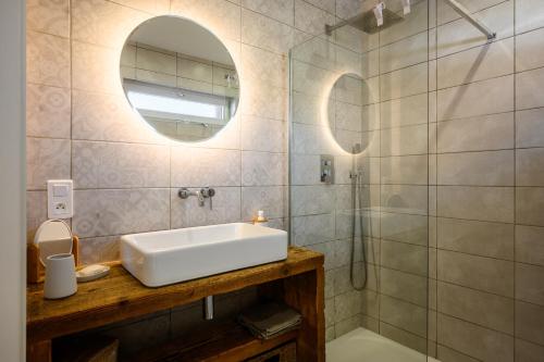 a bathroom with a sink and a shower with a mirror at Flora Gîte in Kaysersberg