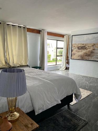 a bedroom with a bed with a lamp and a window at White house Residences by Pebbles in Lusaka