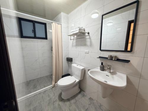 a white bathroom with a toilet and a sink at Si Sou Homestay in Nanxi