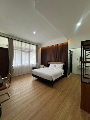 a large bedroom with a bed and a chair at And Living Hotel in Kejayan