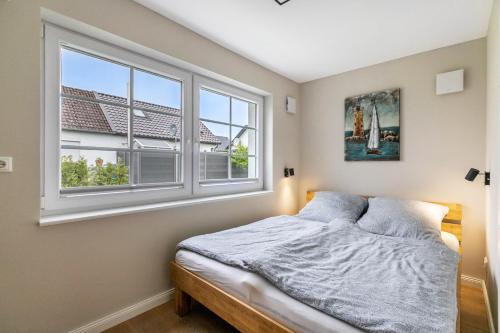 a bedroom with a bed and two windows at Lütte Auszeit in Hennstedt