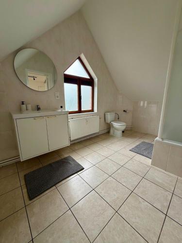 an attic bathroom with a toilet and a window at Het Schuttershof in Hoogstraten