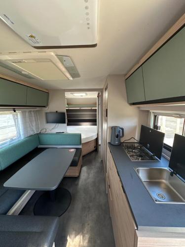 a small kitchen with a caravan with a bed and a sink at HelloHel klimatyzowane przyczepy Jastarnia Surf Kite Wind in Jastarnia