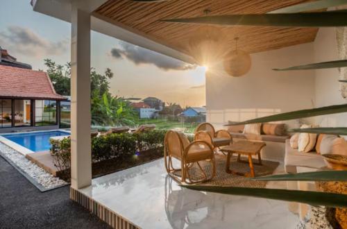 a patio with chairs and a table and a pool at Emy Kerobokan in Kerobokan