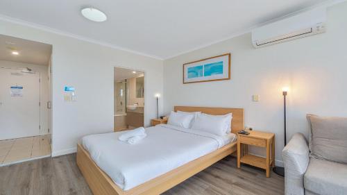 a bedroom with a white bed and a couch at Studio Oasis - Ettalong Beach Resort in Ettalong Beach