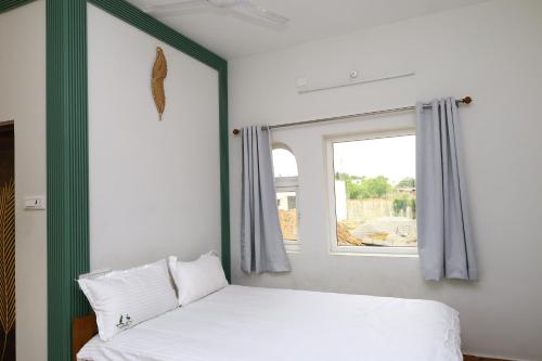 a bedroom with a bed and a window at The Aussie House in Mahabalipuram