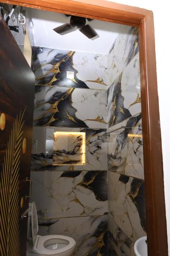 a bathroom with a toilet and a marble wall at The Aussie House in Mahabalipuram