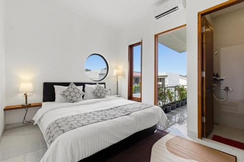 a bedroom with a large bed and a mirror at KAUH House Canggu in Tumbak Bayuh