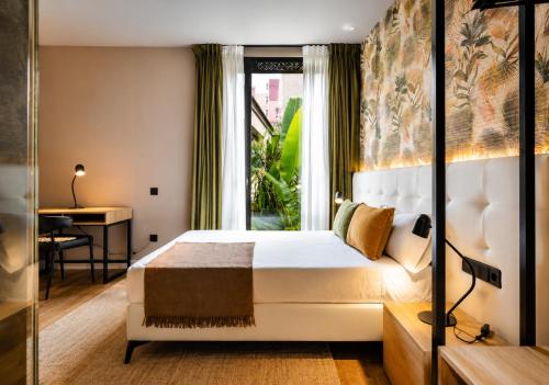 a bedroom with a bed and a desk and a window at Saman Hotel Boutique in Valencia