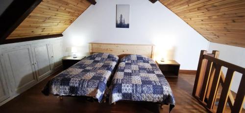 two beds in a room with wooden ceilings at Chez Nicole et Patrick in Chouvigny
