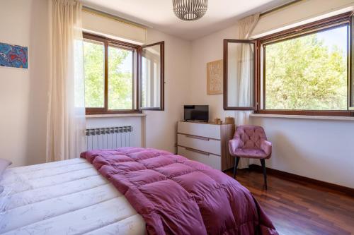 a bedroom with a bed and a chair and windows at Appartamento Posta del Lago in Passignano sul Trasimeno