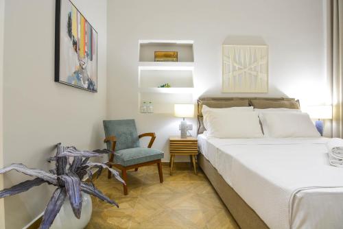 a white bedroom with a bed and a chair at Evilion Suites in Xylokastro