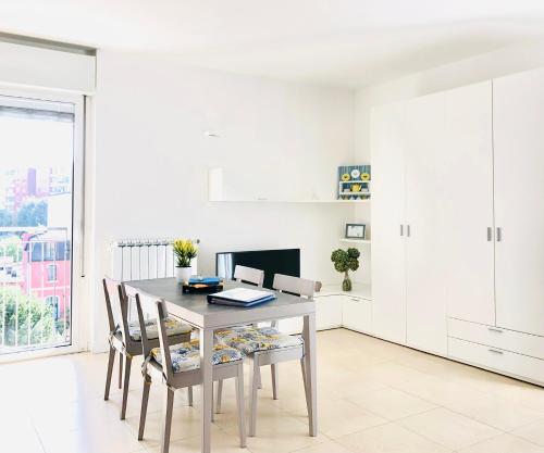 a white dining room with a table and chairs at Stepandgo Milano Navigli in Milan