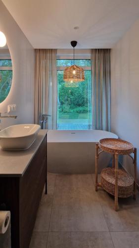a bathroom with a large tub and a sink at Poilsio nameliai TekaTeka in Anykščiai