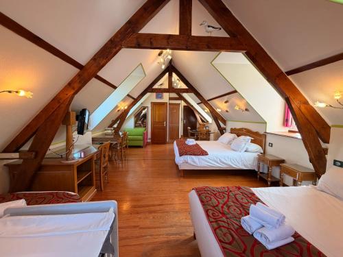 a attic room with two beds and a desk at Hôtel De Calais in Le Tréport