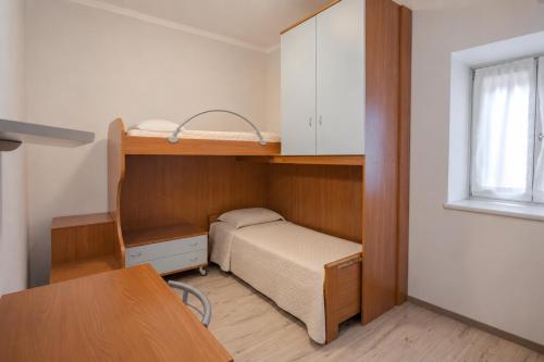 a small room with a bunk bed and a desk at Casa Caorer by Sunhome Fiemme in Predazzo