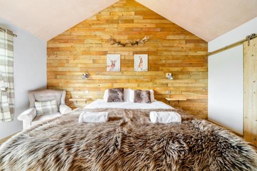 a bedroom with a large bed with a wooden wall at Bwncath in Welshpool