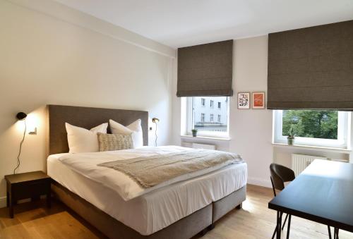 a bedroom with a large bed and two windows at SAXX Apartments Hagen in Hagen