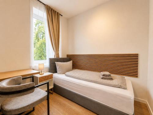 a bedroom with a bed and a chair and a window at Leipzig Garden Rooms - Near Lake & easy Parking in Leipzig