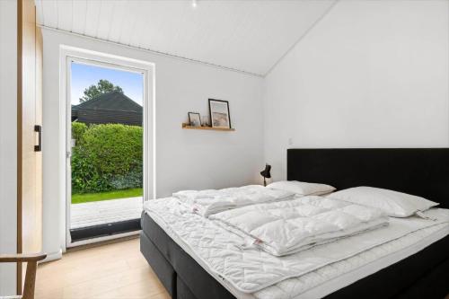 a white bedroom with a bed with a window at 30129-Odder-P-Baatrupsvej-29 in Odder