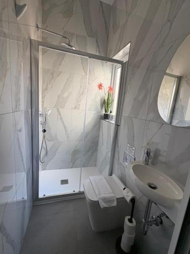 a white bathroom with a shower and a sink at Melita Living in Sliema
