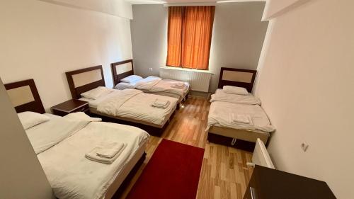 three beds in a small room with a window at METRO Hotel in Gusinje