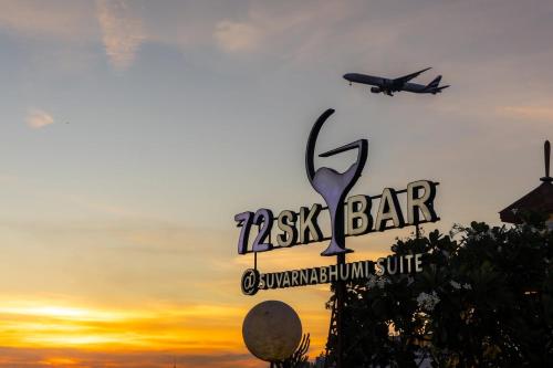 an airplane is flying over a pizza bar sign at sunset at Suvarnabhumi Suite Hotel - Suvarnabhumi Airport, Bangkok in Lat Krabang
